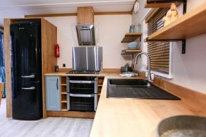 uma cozinha com um frigorífico preto e um lavatório em Sandy Balls Holiday Village em Fordingbridge
