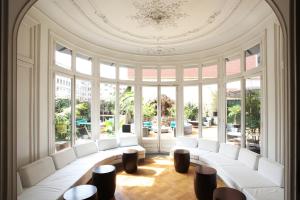 a large room with white chairs and tables and windows at Praktik Rambla in Barcelona