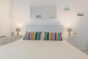 Una cama blanca con dos almohadas coloridas. en Guesthouse Green Istria en Truške