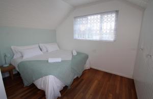 a white bedroom with a bed and a window at Back-Up Power with Stable WiFi! Central in Walmer in Port Elizabeth