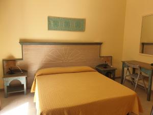 a bedroom with a bed with an orange bedspread at Hotel La Valle in Carloforte