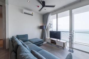 a living room with a blue couch and a tv at 3BR Seaview/HighFloor/Veranda Residence Pattaya in Jomtien Beach