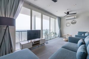 ein Wohnzimmer mit einem blauen Sofa und einem TV in der Unterkunft 3BR Seaview/HighFloor/Veranda Residence Pattaya in Jomtien Beach