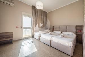 a bedroom with two beds and a window at Inn Hotel in Durrës