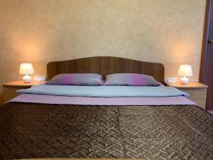 ein Schlafzimmer mit einem Bett mit zwei Lampen auf beiden Seiten in der Unterkunft Апартаменты LUX в центре in Angarsk