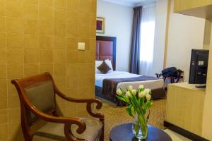 a hotel room with a bed and a vase of flowers at Kingsgate Hotel Doha by Millennium Hotels in Doha