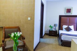 a hotel room with a bed and a vase of flowers on a table at Kingsgate Hotel Doha by Millennium Hotels in Doha
