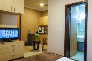 a living room with a television and a kitchen at Kingsgate Hotel Doha by Millennium Hotels in Doha