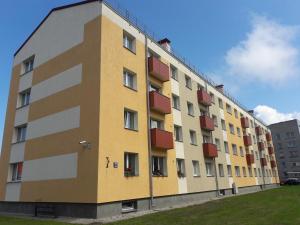 un grand bâtiment jaune et blanc avec des balcons rouges dans l'établissement Dzīvoklis, à Ventspils