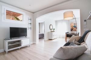 uma sala de estar com um sofá e uma televisão de ecrã plano em Apartamentos Hotel Pirineos em Figueres