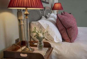 una mesa con una lámpara y un jarrón de flores en una cama en Glenburnie at Thirlestane Castle en Lauder