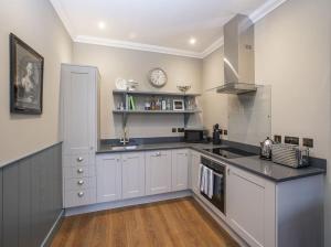 a kitchen with white cabinets and a clock on the wall at Glenburnie at Thirlestane Castle in Lauder