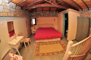 een slaapkamer met een rood bed in een kamer bij Oreiades Houses in Kardítsa