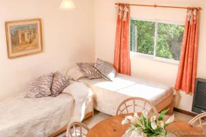 1 dormitorio con 2 camas, mesa y ventana en Soles Blancos Serranita en Alta Gracia