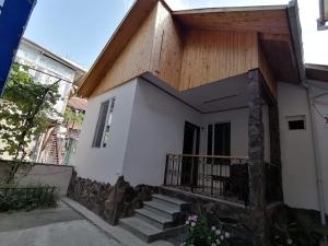 una piccola casa bianca con tetto in legno di Ira & Vaso's guest house Borjomipark a Borjomi