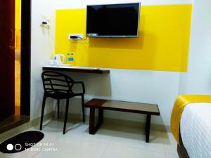 a room with a desk with a chair and a tv at Hotel Nirvana in Alibaug