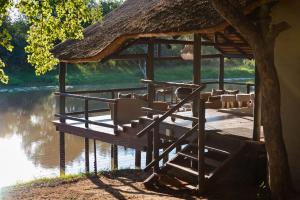 a pavilion with chairs on a dock next to a river at Malilule Safaris in Hoedspruit