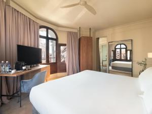 a hotel room with a large bed and a television at H10 Palacio Colomera in Córdoba