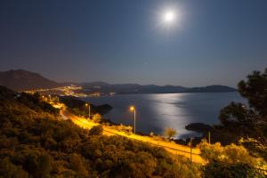 a night view of a road with the moon over the water at Hamarat Otel in Kaş