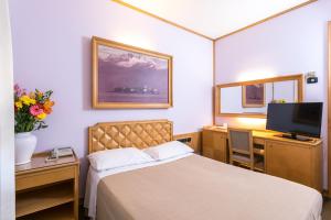 a bedroom with a bed and a desk and a tv at Albergo Italia in Novara