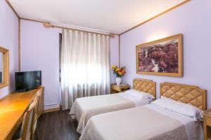 Cette chambre comprend deux lits et une télévision. dans l'établissement Albergo Italia, à Novara