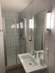 ein weißes Bad mit einem Waschbecken und einer Dusche in der Unterkunft Hotel und Apartment Garni Eurode Live in Herzogenrath