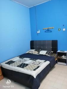 a blue bedroom with a bed with a black headboard at BB HOMESTAY in Kampung Tualang +3 photos