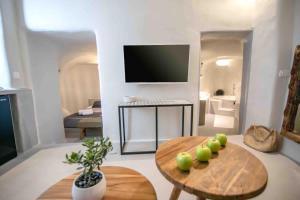 a living room with a table, chairs and a tv at Santorini Villas in Vourvoulos