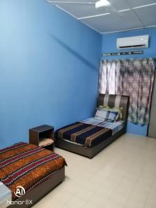 two beds in a room with a blue wall at BB HOMESTAY in Kampung Tualang