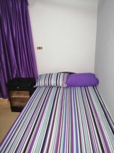 a bedroom with a striped bed with purple curtains at Al Dahar apartments Hurghada in Hurghada