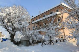 un bâtiment avec des arbres enneigés devant lui dans l'établissement Albergo Ristorante Sterlina, à Grizzana