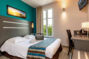 a hotel room with a bed and a desk and a window at Hotel Terminus Saint-Charles in Marseille