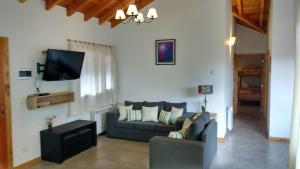 a living room with a couch and a tv at Búngalows Osa Mayor in Villa La Angostura