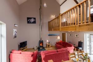 a living room with red chairs and a staircase at Kidwelly Farm Cottage in Kidwelly