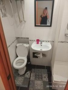 une femme prenant une photo d'une salle de bains avec toilettes et lavabo dans l'établissement Apartment on Danyla Galytskogo 8A, à Morshin