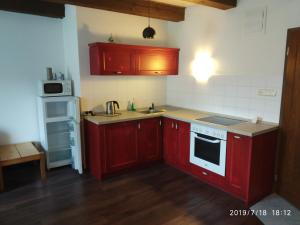 eine Küche mit roten Schränken und einem weißen Kühlschrank in der Unterkunft Apartments Cederika in Věžovatá Pláně