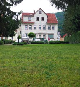 une grande maison blanche avec une pelouse verte en face de celle-ci dans l'établissement Pension Kreihe im Harz, à Bad Lauterberg