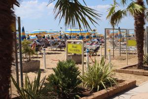 una spiaggia con sedie e ombrelloni e un cartello di Villa Serena a Lido di Jesolo