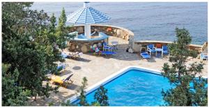 an overhead view of a swimming pool with chairs and an umbrella at Daidalos Hotel in Armenistis