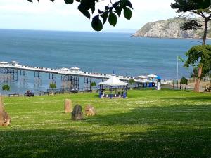 a park with a pier in the water and a beach at Branstone Guest House in Llandudno