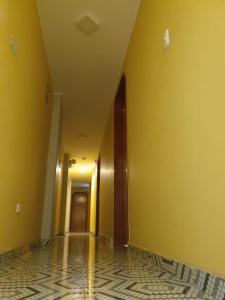 un pasillo vacío con paredes amarillas y suelo de baldosa en HOSTAL EL TORNILLO, en Lima