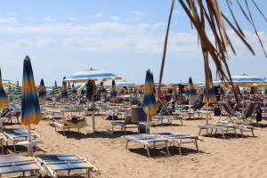 um monte de cadeiras e guarda-sóis numa praia em Villa Serena em Lido di Jesolo