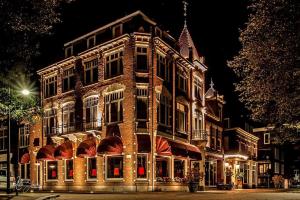 een groot bakstenen gebouw 's nachts met lichten aan bij Augusta Hotel in IJmuiden