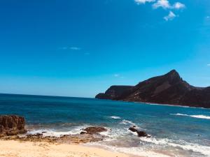 a beach with the ocean and mountains in the background at Casinha Vista Mar in Porto Santo +12 photos