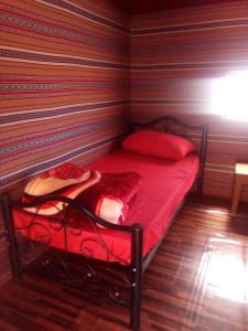 a small bedroom with a red bed in a room at Wadi Rum Caravan Camp in Wadi Rum