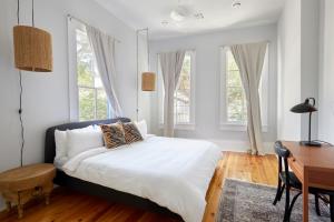 een slaapkamer met een bed, een bureau en ramen bij Sonder at Uptown in New Orleans