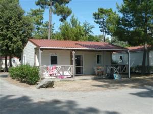 una pequeña casa blanca con techo rojo en Camping Le California, en Saint-Jean-de-Monts