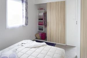 a bedroom with a white bed and a window at Camping Le California in Saint-Jean-de-Monts