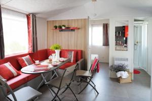 a living room with a red couch and a table at Camping Le California in Saint-Jean-de-Monts