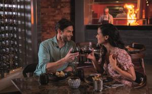 a man and woman sitting at a table with wine glasses at Planet Hollywood Adult Scene Cancun, An Autograph Collection All- Inclusive Resort - Adults Only in Canc&uacute;n